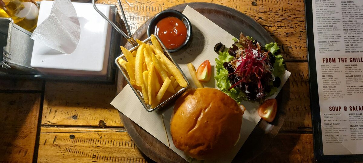 Hamburguesa Ruda con patatas fritas y ensalada servida en tabla de madera