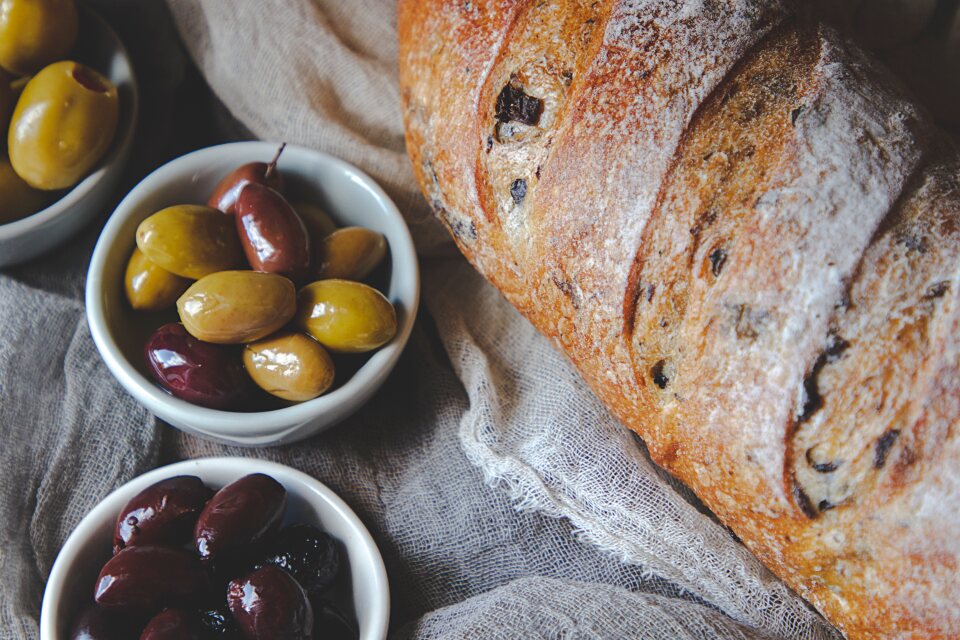 Hogaza de pan de masa madre recién horneada con aceitunas aliñadas